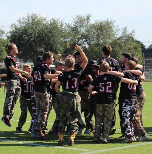 Senior varsity football players jump and yell during the Victory Cheer.