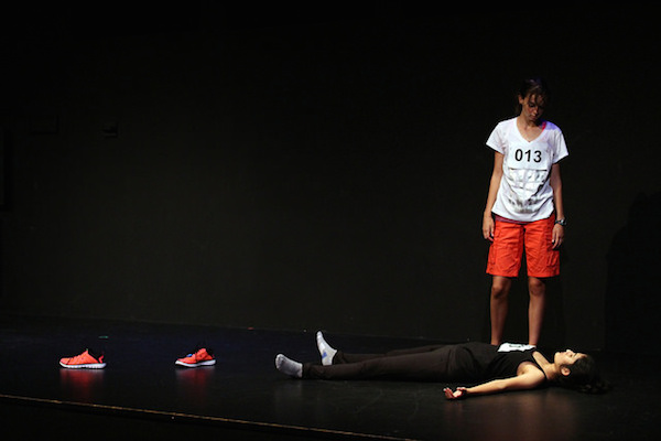 Freshman Abigail Price stands over sophomore Manar Ansari in the one-act Gel Us, in which their characters Kathy and Laura attempt a marathon. 