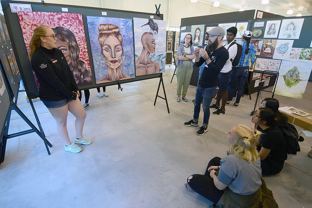 Sophomore Morgan Self, left, presents her series of large acrylic paintings.