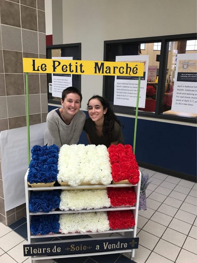 Sophomores Juliana and Josephine get behind a flower market in the halls of Atascocita High school. 
