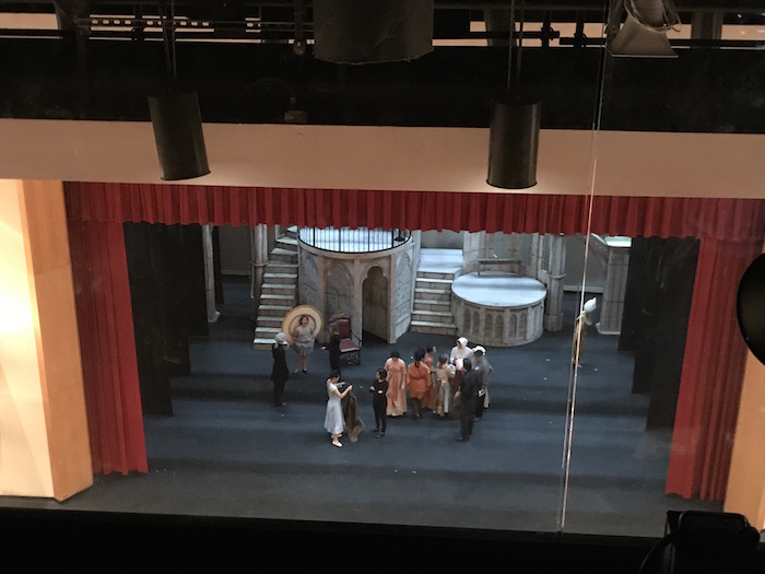 The cast of Beauty and the Beast assembles onstage while techs set up lights for the performance.