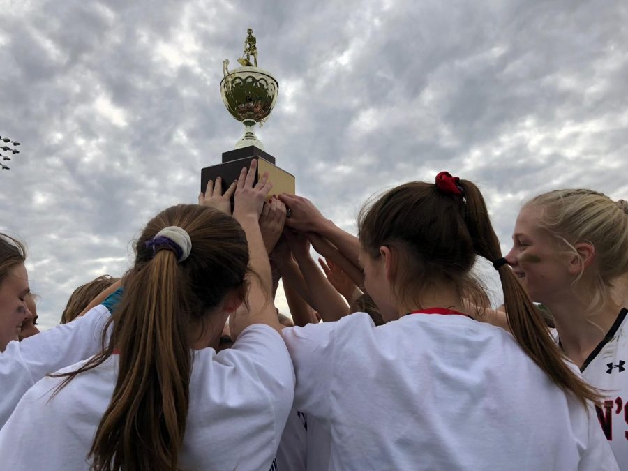 The field hockey team lifts their SPC trophy.