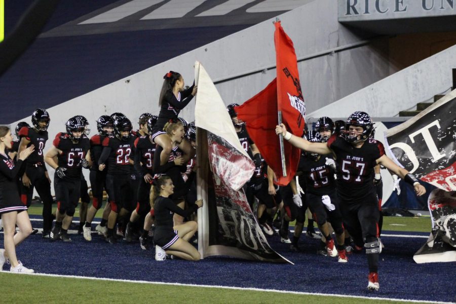 The football team bursts through the Not Without Honor banner to begin the game. 