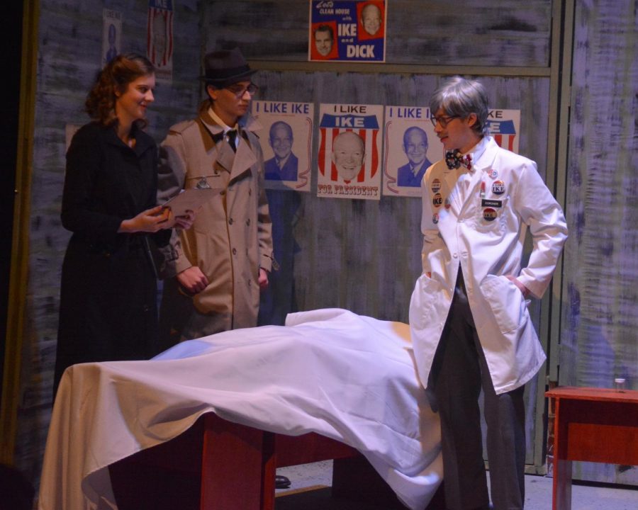 Maggie Pelletier (played by Sacha Waters) and Frank Keller (played by Eli Maierson) examine the results of the autopsy conducted by the doctor (played by George Hagle).