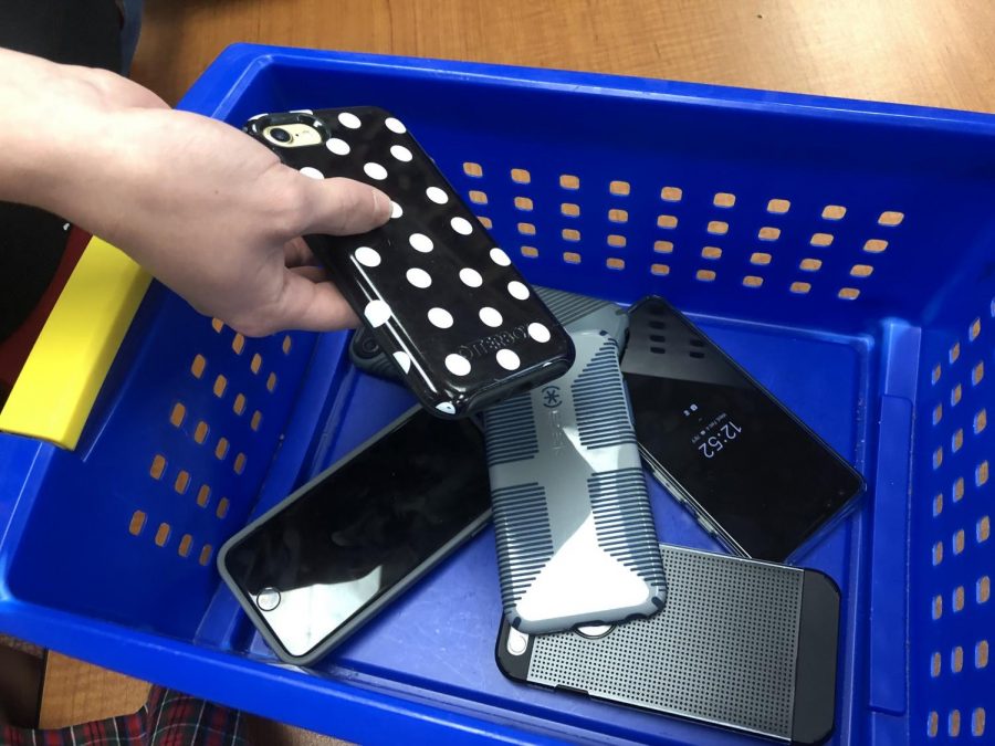 Students placing their phones in a collection box before class.