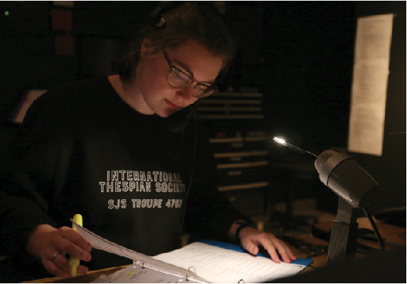 Stage manager Lucy Curtis works in the sound booth, following along in her script as actors run scenes in Lowe Theater. As stage manager, she organizes the shows cast, gives backstage cues and facilitates communication between director and the set crew.