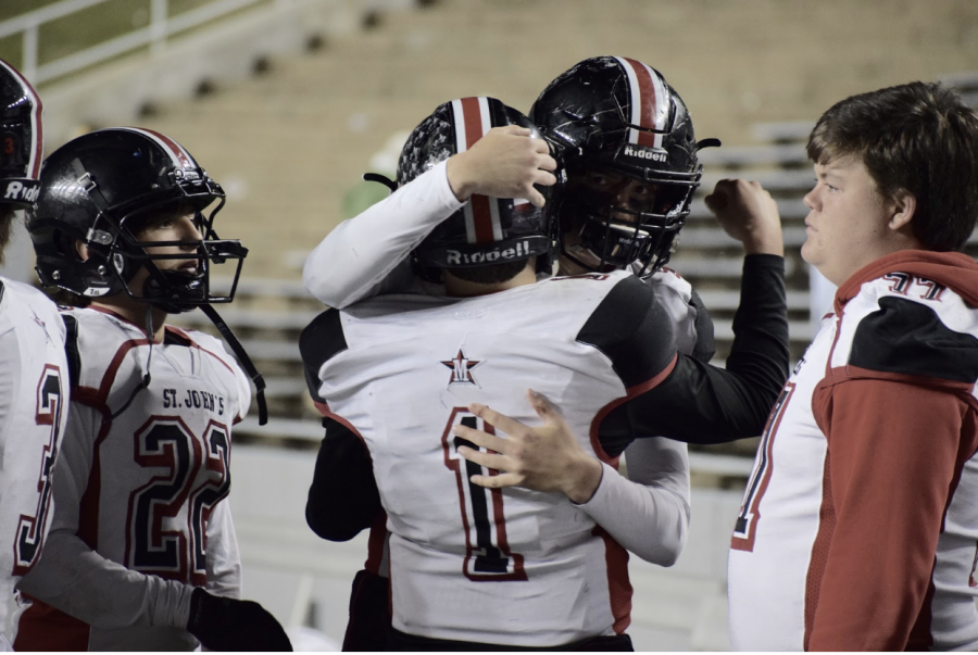 Defensive back Peter Cannon embraces quarterback George Caldwell (No. 1) after Cannon’s final game as a Maverick.