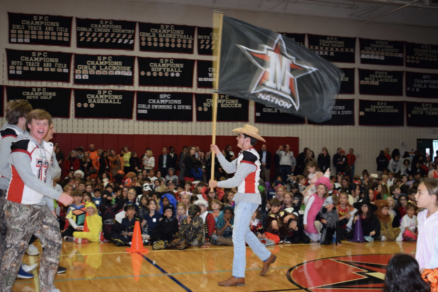 Quarterback George Caldwell carries the Mav Nation flag down to mimic the tradition of planting the flag in the center of Skip Lee Field. The Pep Rally was moved inside due to inclement weather.