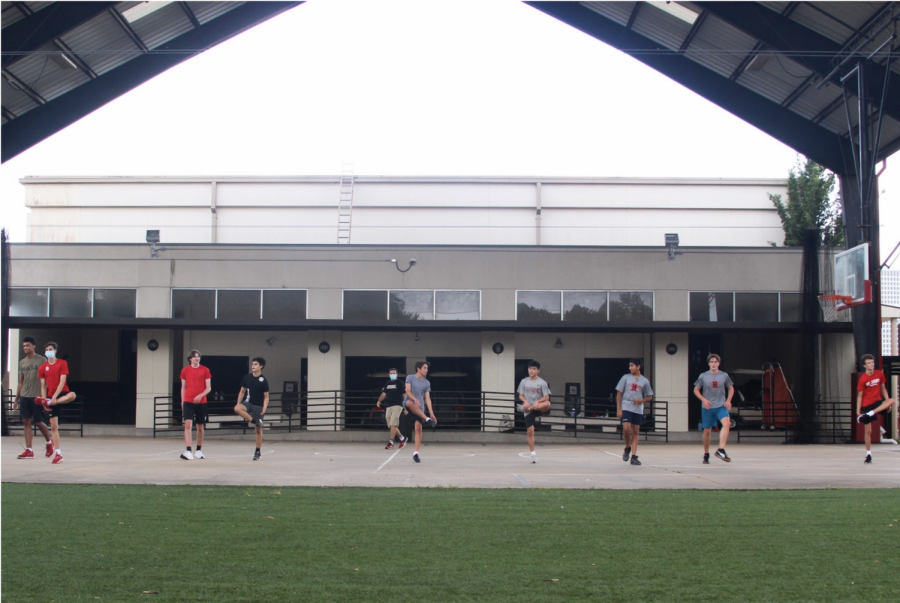 The boys volleyball team stretches underneath “Big Red,” the outdoor basketball court.