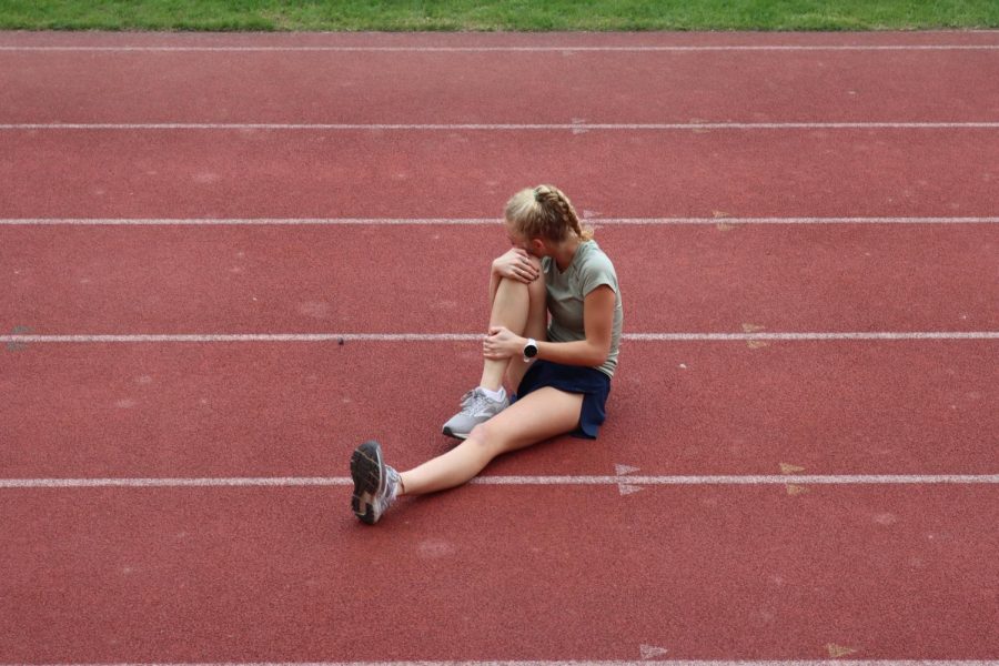 Junior Alexa Christensen rests on the track after a long and tiring day of classes and sports practice.