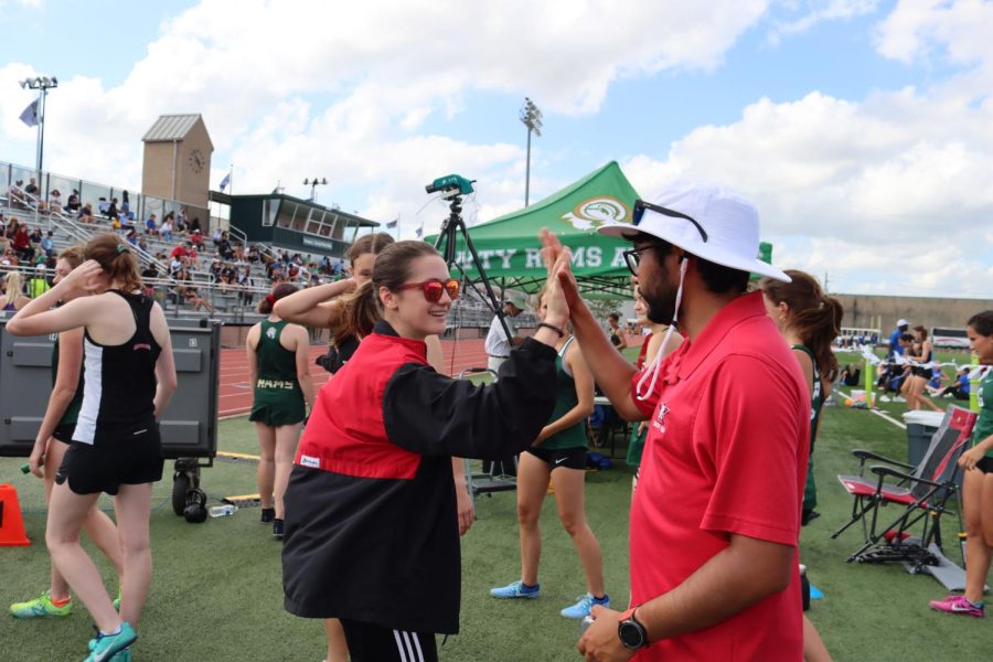 Coach Balderas high fives senior Cici Calhoun before she races in the 4x800m.