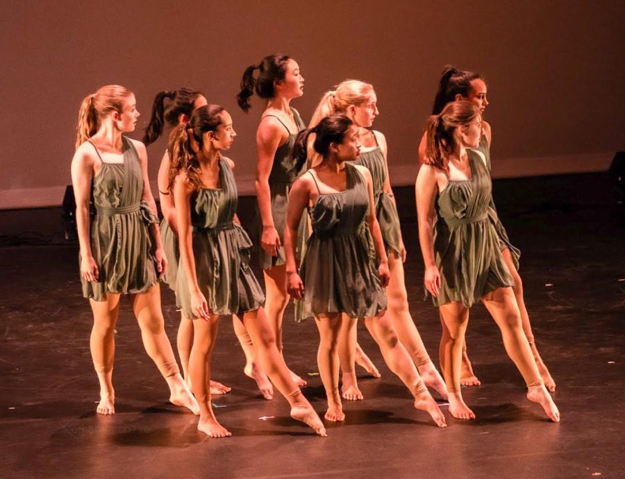 Eight dancers dressed in bright colors begin their dance routine.