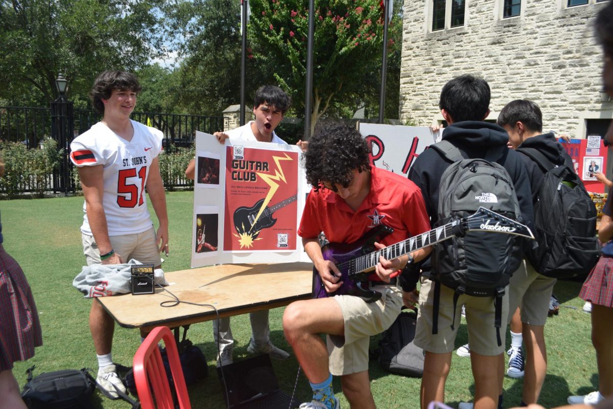 Senior Ajay Clark-Desai strums lively tunes in front of the Guitar Club booth. 