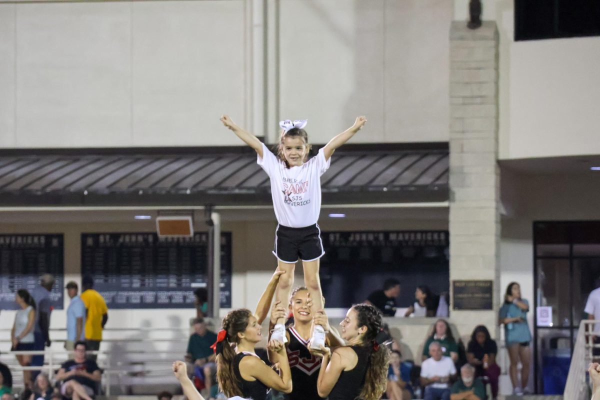 Class One student Mackenzie Veltri, a graduate of the summer cheer camp, performs at halftime with the varsity cheerleaders.
