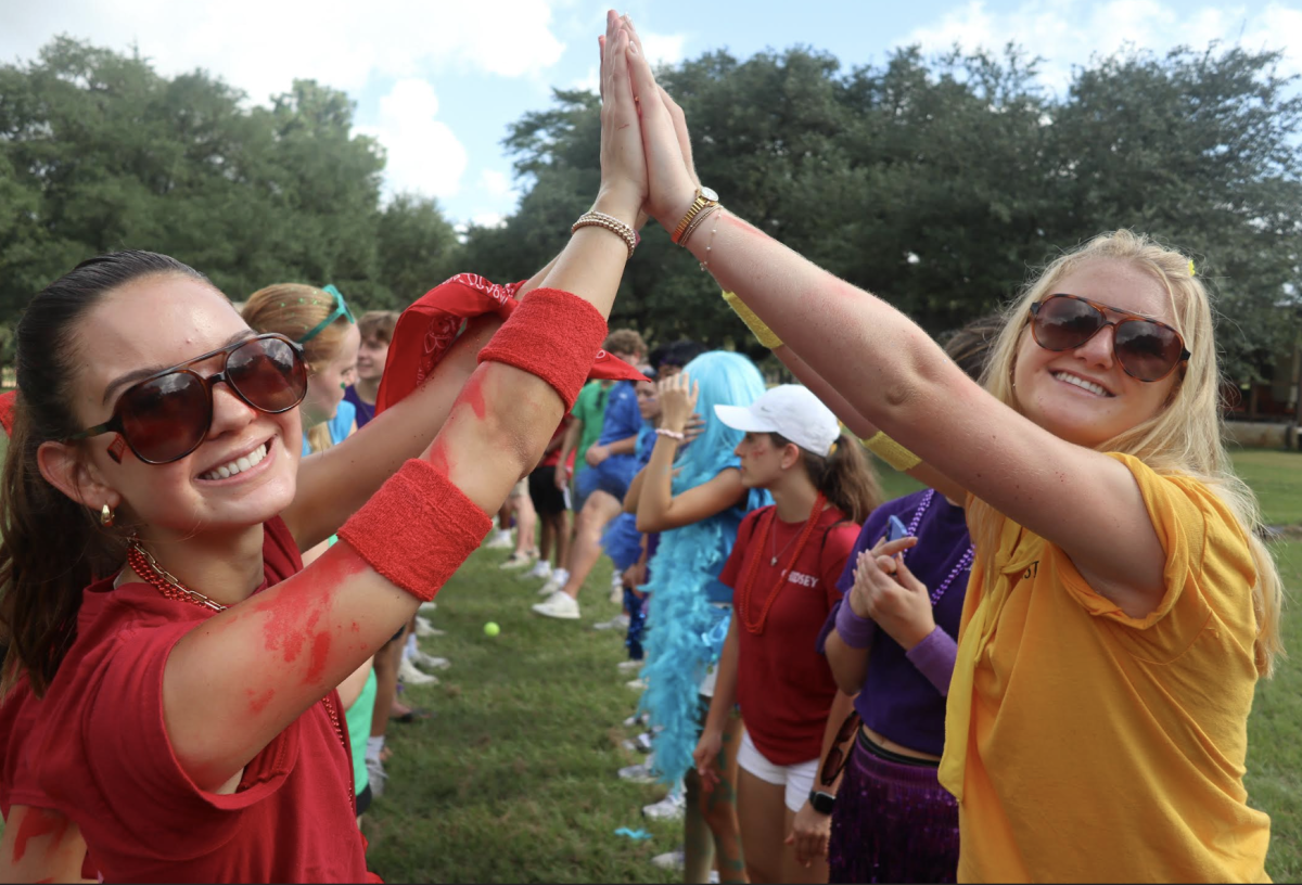 Seniors Catherine Cox and Josephine VanHoutan form the first link of a hand bridge for incoming freshmen to run through. Courtesy of Marty Thompson.